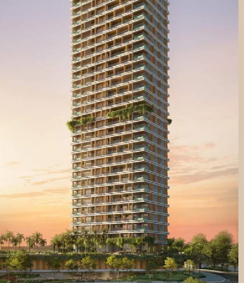 Fachada do edifício residencial de alta estatura com terraços verdes e base arborizada ao entardecer