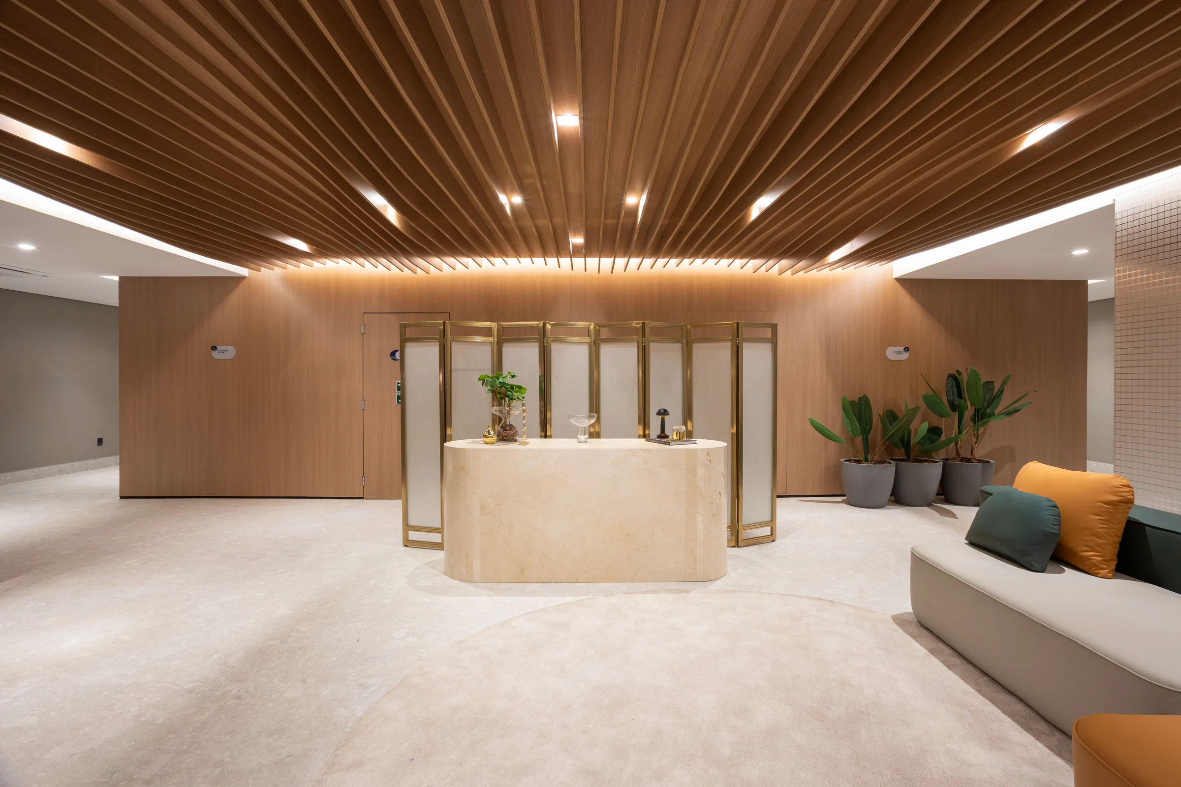 Lobby de entrada com recepção, forro de madeira ripada e área de estar